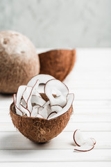 Coconut chips in a brown bowl on a white wooden background