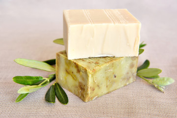 Handmade soap bars and olive branches on gunny background