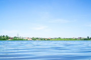 Private houses with red roofs on the horizon. River and blue sky. In the light. light tone....