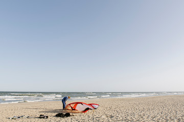 Male surfer preparing a kite at the beach