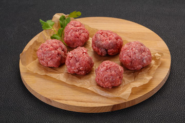 Raw meatball over wooden background