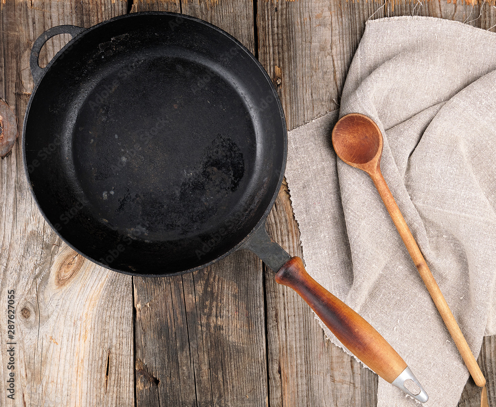 Poster empty black round frying pan with handle and spoon