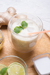 fresh vegetarian banana - ginger cocktail on wooden tray with fresh  bananas,  lime, melissa and coconut milk  . close up