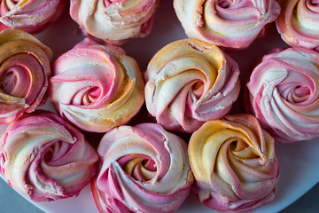 Beautiful bright multi-colored homemade marshmallow in the form of roses on a white plate.