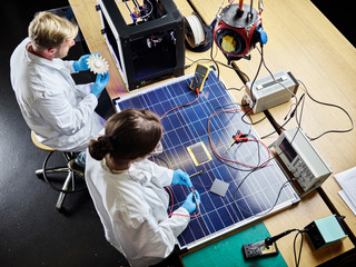Two technicians working on d printed turbine wheel and solar panel in lab