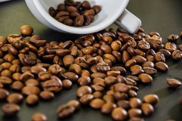 Coffee beans scattered from a cup on a black background. Close-up.