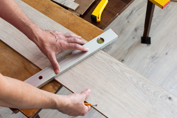Installation laminate or parquet in the room, worker installing wooden laminate flooring, marking the length of the laminate