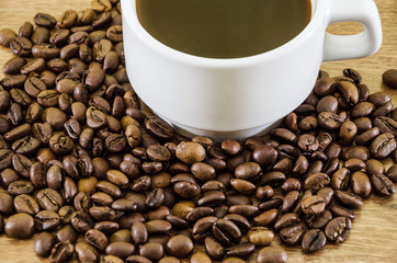 cup of coffee and a pile of coffee beans on a wooden background. Close-up.