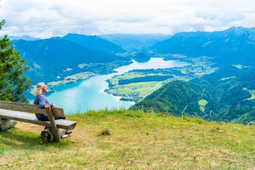 A male admires view of Wolfgangsee lake and surrounding mountains from Zwolferhorn mountain in St. Gilgen in Salzkammergut region, Austria
