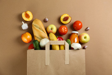 Bunch of mixed organic fruits, vegetables & greens, gourmet pile in full eco friendly shopping bag to reduce ecological footprint. Zero waste concept. Brown table background, copy space, close up.