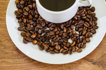 cup of coffee and a pile of coffee beans on a wooden background. Close-up.