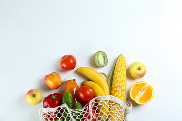 Bunch of mixed organic fruits, vegetables & greens, gourmet pile in full eco friendly shopping bag to reduce ecological footprint. Zero waste concept. White table background, copy space, close up.