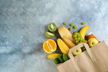 Bunch of mixed organic fruits, vegetables & greens, gourmet pile in full eco friendly shopping bag to reduce ecological footprint. Zero waste concept. Grunged stone background, copy space, close up.