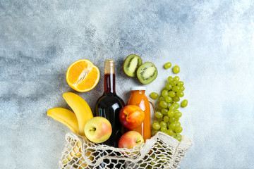 Bunch of mixed organic fruits, vegetables & greens, gourmet pile in full eco friendly shopping bag to reduce ecological footprint. Zero waste concept. Grunged stone background, copy space, close up.