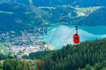 View of St.Gilgen village, Wolfgangsee lake and red Seilbahn cable car gondolas from Zwolferhorn mountain in Salzkammergut region, Austria