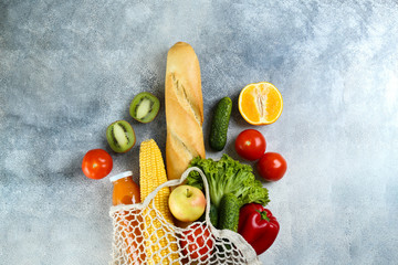 Bunch of mixed organic fruits, vegetables & greens, gourmet pile in full eco friendly shopping bag to reduce ecological footprint. Zero waste concept. Grunged stone background, copy space, close up.