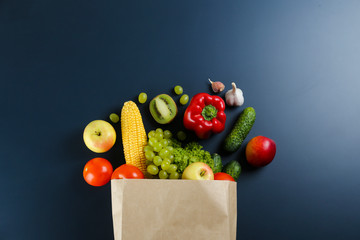 Bunch of mixed organic fruits, vegetables & greens, gourmet pile in full eco friendly shopping bag to reduce ecological footprint. Zero waste concept. Graphite table background, copy space, close up.