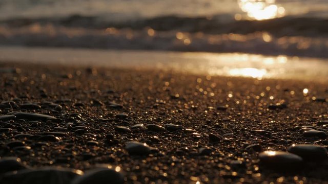 The sun rises over the sea at dawn. Sea surf and pebbles in the morning sun.
