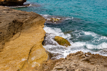 View at the rocky coastline in Cala Rajada on balearic island Mallorca, Spain on a sunny day with clear turquoise water and waves