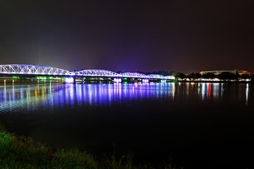 Night scene of illuminated bridge over a river in the distance.Hue, Vietnam