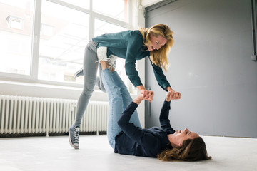 Two young women supporting each other playfully