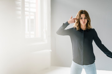 Young woman making hand sign, shooting herself