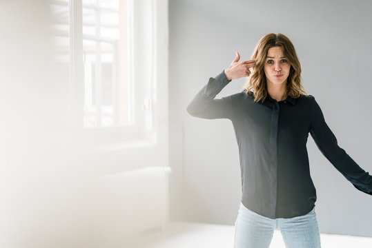 Young woman making hand sign, shooting herself