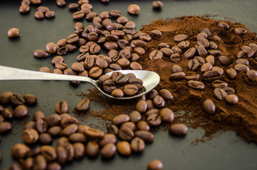 coffee beans in a spoon against a background of scattered coffee beans and ground coffee.