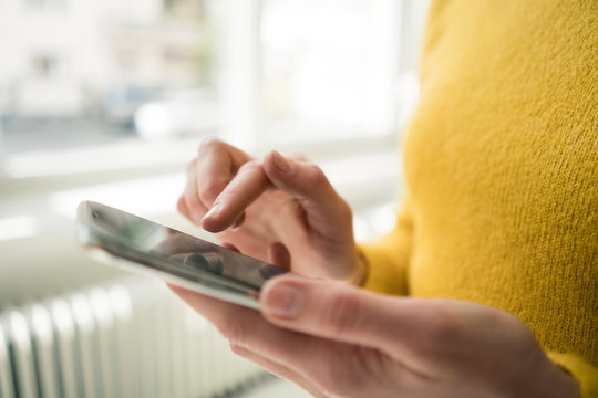 Woman in yellow pullover, using smartphone