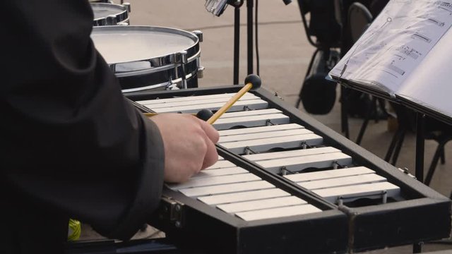Male hands playing music on vibraphone or metallophone on outdoor concert. Musian playing melody by glockenspiel on street performance. Live music on city event