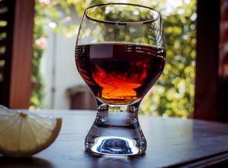 Brandy or cognac, whiskey in the glass with lemon on table. Wooden table background texture. Brown strong alcohol drink for relaxation and nightclub.