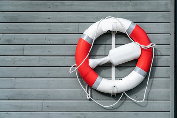Red orange life rescue buoy hanging on a blue wooden wall.