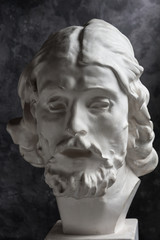 Gypsum copy of ancient statue John the Baptist head on dark textured background. Plaster sculpture...