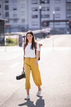 Young woman carrying violin case walking on the street