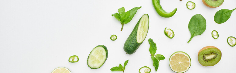 panoramic shot of fresh cucumbers, kiwi, limes, peppers and greenery
