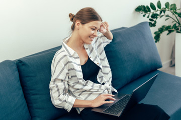 Young adult woman using modern laptop and smiling