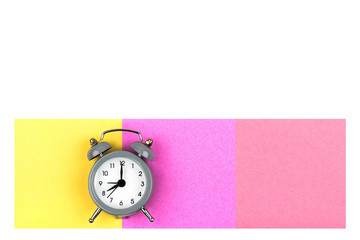 Clock with an alarm clock on a white background lie on colored paper leaves of yellow and raspberry color for notes