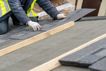 Workman install tile on roof of new house under construction