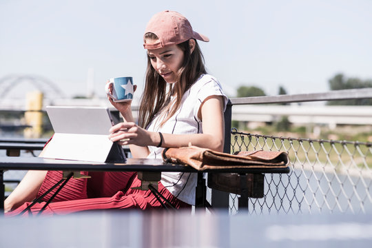 Young woman relaxing in a beer garden using tablet