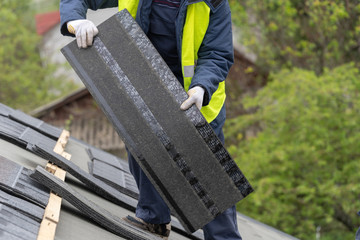Workman install tile on roof of new house under construction
