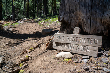Damaged wooden sign indicating unrestricted camping beyond this point
