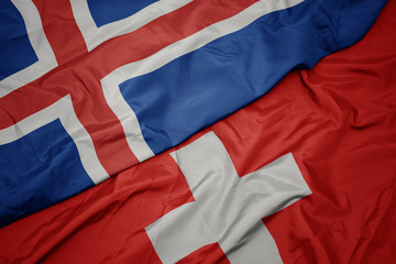waving colorful flag of switzerland and national flag of iceland.