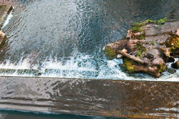 Water from the river Viliya flows through the wall, view from above, close-up.
