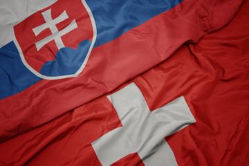 Fototapeta premium waving colorful flag of switzerland and national flag of slovakia.