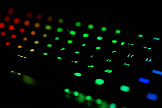 Diagonal RGB gaming keyboard bokeh background. Colorful mechanical keyboard in dark room. Gaming and technology concept © Dawid G