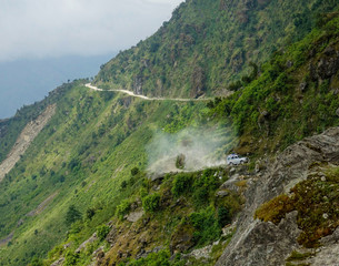 Tourists on road trip to Tibet drive a jeep down a dirt road in the Himalayas.