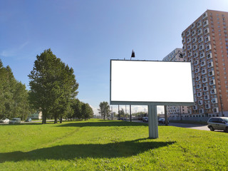 large billboard advertising in the city on a green lawn and against a blue sky