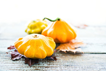 Yellow pumpkins and autumn leaves on old wooden  table