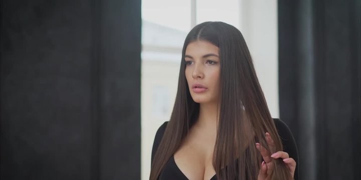 A beautiful sexy brunette walks along the window. Portrait of a beautiful Indian Bengali brunette woman wearing a black top looking thoughtfully while standing near a window full of light. Indian