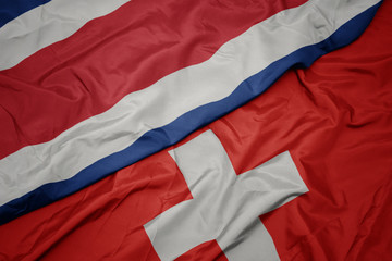 waving colorful flag of switzerland and national flag of costa rica.